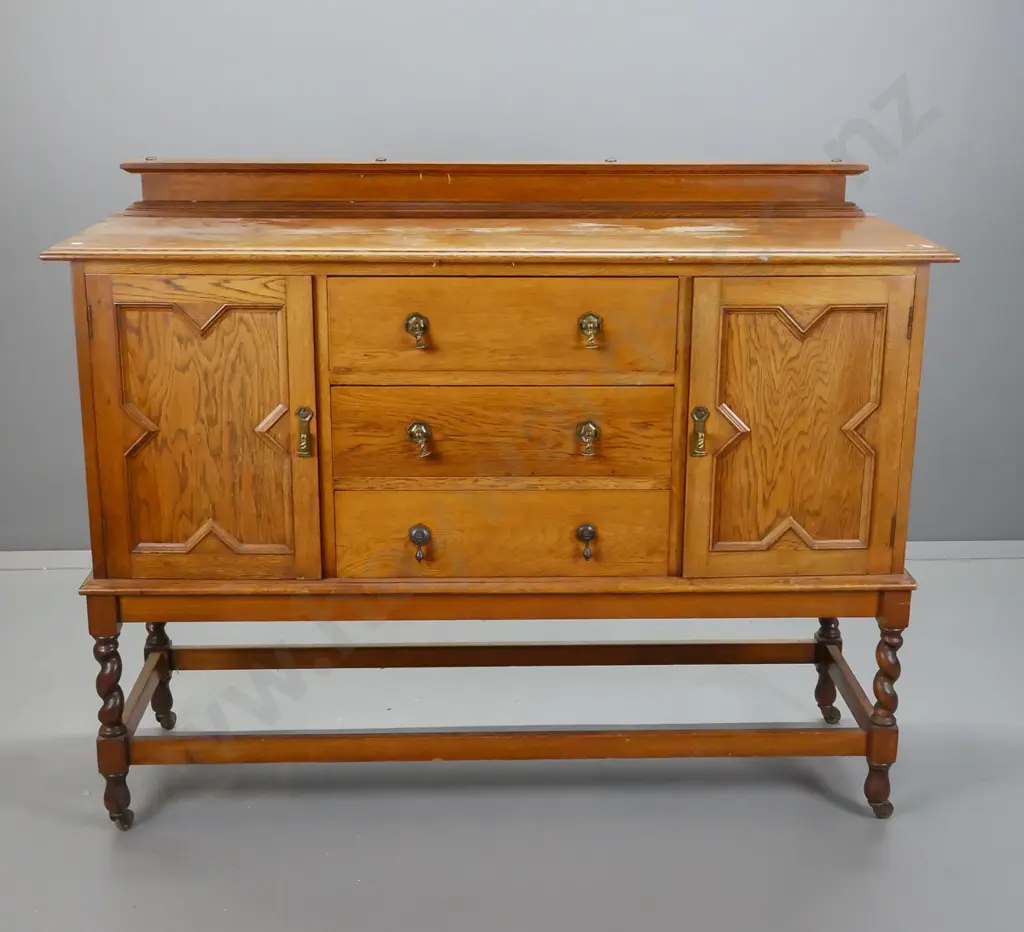 vintage oak Tudor style sideboard with 2 panelled doors, 3 drawers, brass drop handles, stretcher base with twist legs Image 1++