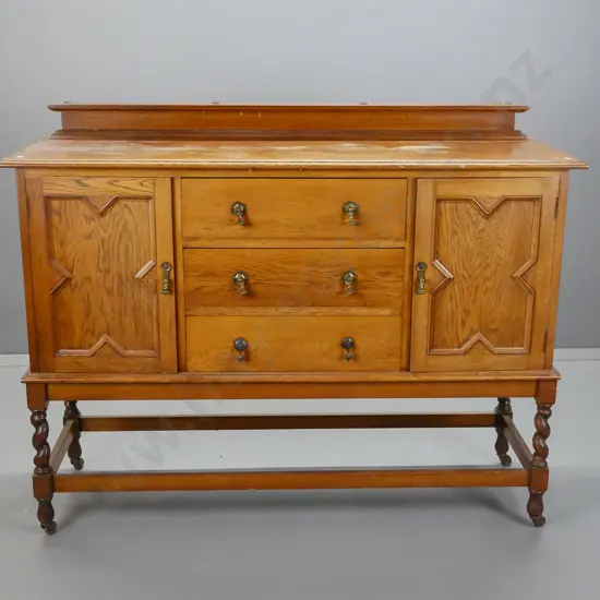 vintage oak Tudor style sideboard with 2 panelled doors, 3 drawers, brass drop handles, stretcher base with twist legs