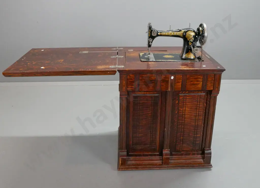 vintage Jones treadle sewing machine in figured oak cabinet with fold-out top linked to lift mechanism, 2 doors Image 1++