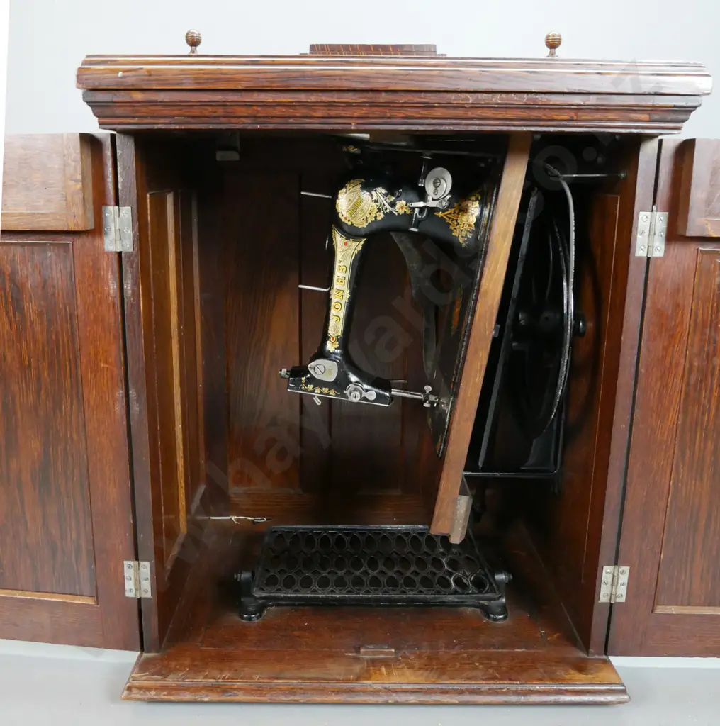 vintage Jones treadle sewing machine in figured oak cabinet with fold-out top linked to lift mechanism, 2 doors Image 1++