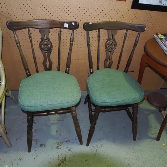 pair of splat back wooden dining chairs with green cushions