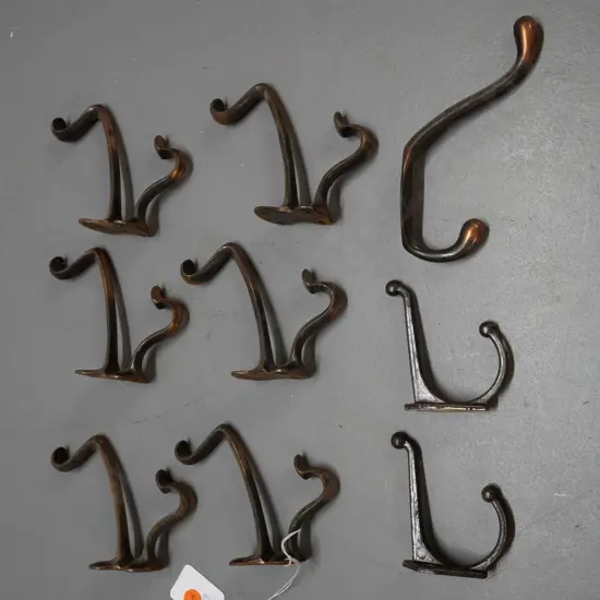 9 vintage cast metal double coat hooks - assorted shapes, some copper finish, some surface corrosion, larger are