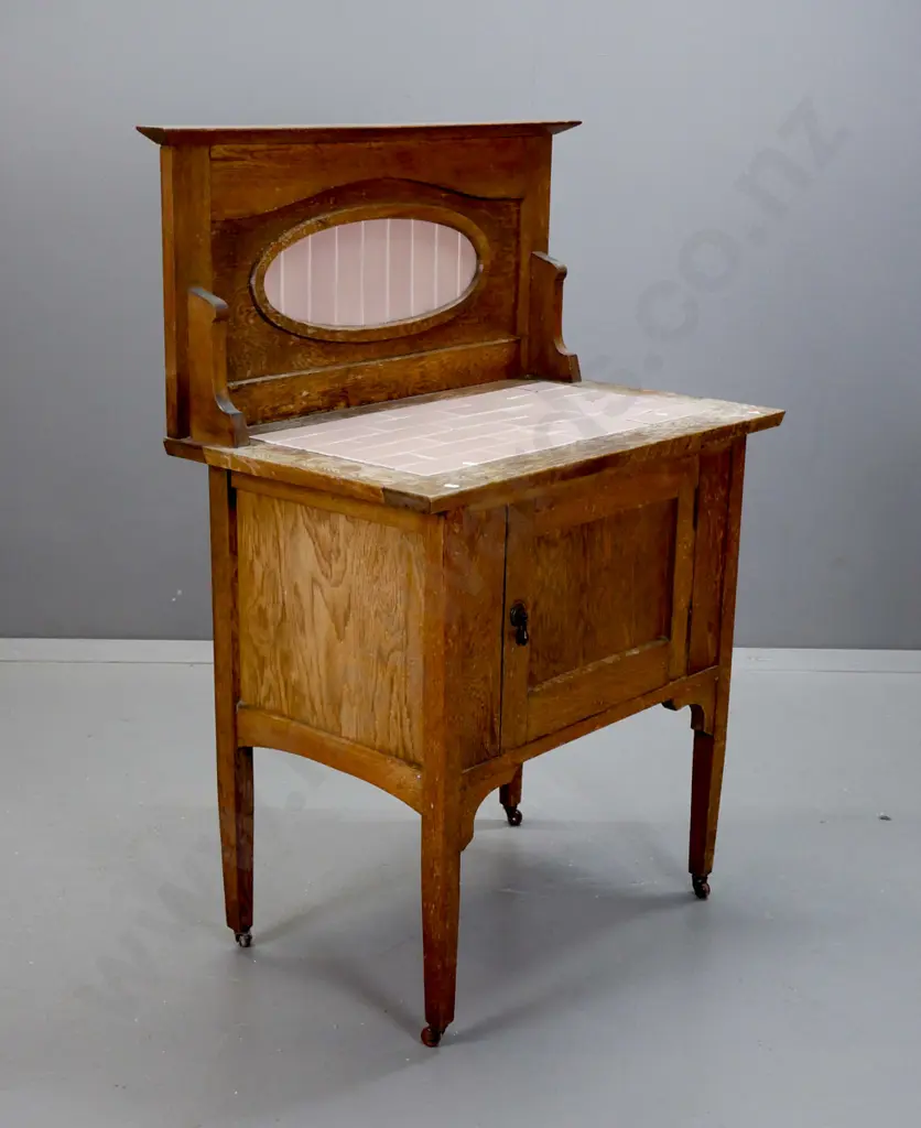 art deco oak wash stand with inset pink tiles in oval framed back and top, cupboard door with drop handle, on porcelain Image 1++