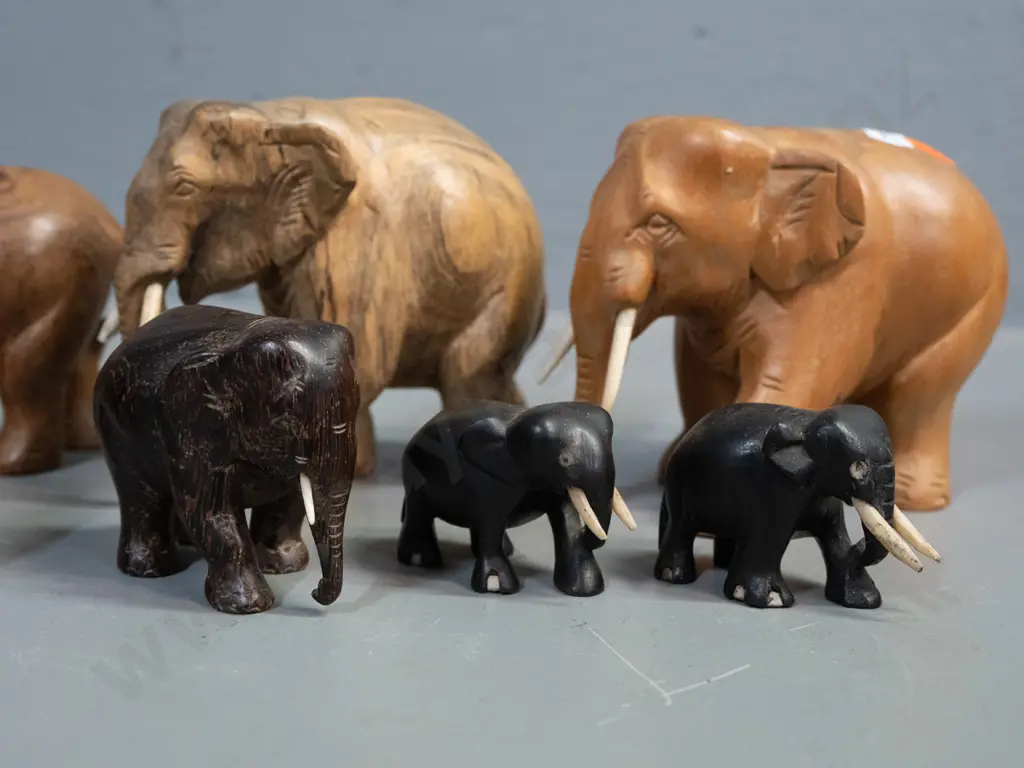 7 small carved teak, ebony and other hardwood elephants - one missing one tusk. Largest is H-95 L-110 Image 1++