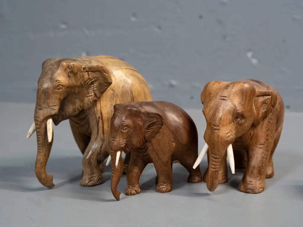 7 small carved teak, ebony and other hardwood elephants - one missing one tusk. Largest is H-95 L-110 Image 1++
