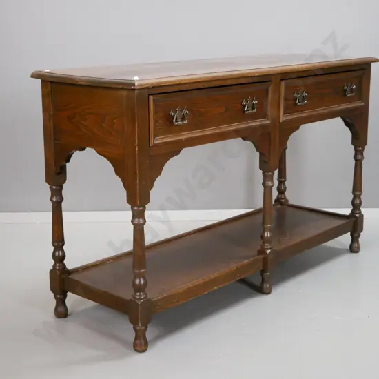 country oak style 2-drawer dresser base with shaped cutout corners, turned legs, bottom shelf, brass handles - some wear