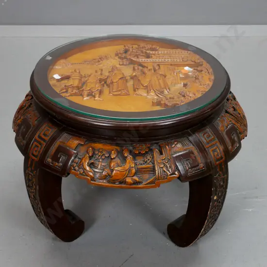 vintage Chinese round table with carved top and sides on 4 sweeping carved legs, glass top over carved scholar scene.