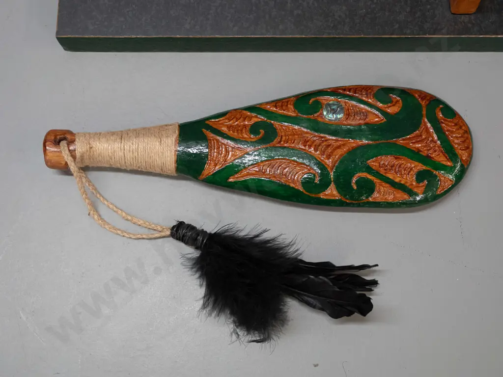 ornamental timber patu with painted decoration, paua insets, cord bound handle and black feathers, with display stand. Image 1++