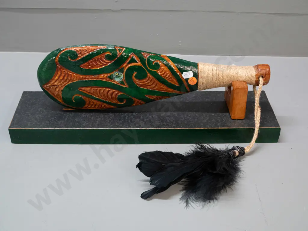 ornamental timber patu with painted decoration, paua insets, cord bound handle and black feathers, with display stand. Image 1++