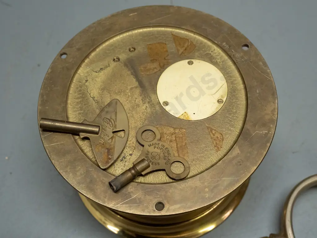 "Boston" brass ship's clock with screw-off face, 2 winding keys, strikes bells (working), and a  pair of brass rowlocks. Image 1++