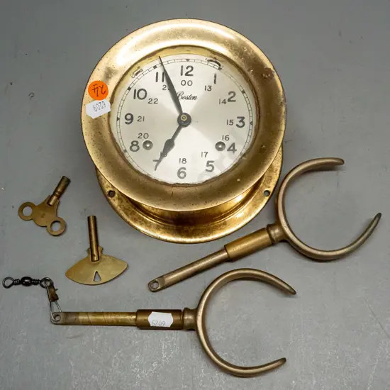 "Boston" brass ship's clock with screw-off face, 2 winding keys, strikes bells (working), and a  pair of brass rowlocks.