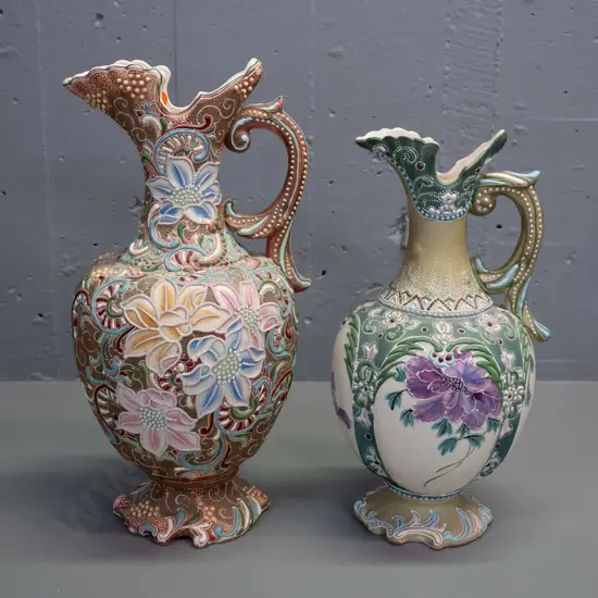 2 Amphora style handled ewer jug vases with raised decoration and floral panels - larger is H-375