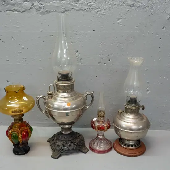 4 kerosene lamps: 2 Miller USA, larger one with dents, other w/ timber base added, and 2 coloured glass, all with clear