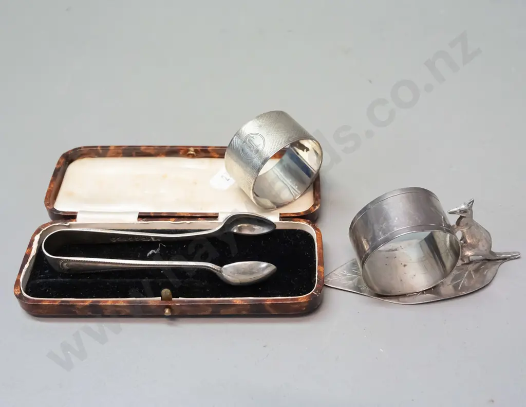 napkin ring with leaf & kangaroo marked Stg Silv, a hallmarked sterling napkin ring and pair of plated sugar tongs Image 1++