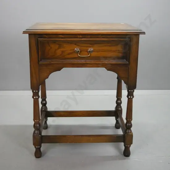 oak side table with single drawer, brass swan neck handle, arched sides and front, turned legs on stretcher base H740
