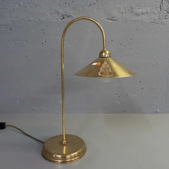brass desk or table lamp with fixed curved stem, spun brass and white enamel shade. Small dent to base, some wear to
