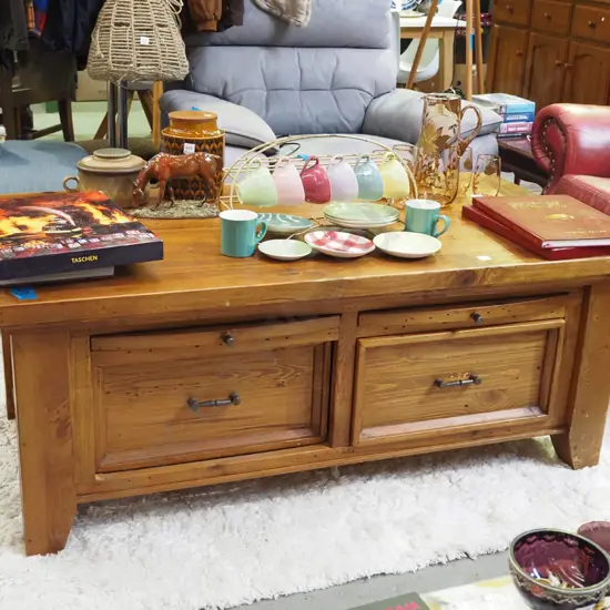 heavy pine coffee table with 2 pull through drawers and 4 pull out shelves - some wear to varnish
