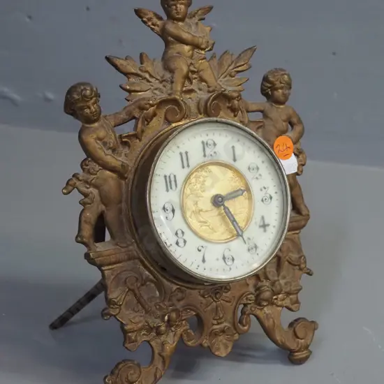 ornate vintage clock in gilded cast metal case with gilded metal and porcelain face, glow in the dark detail on hands,