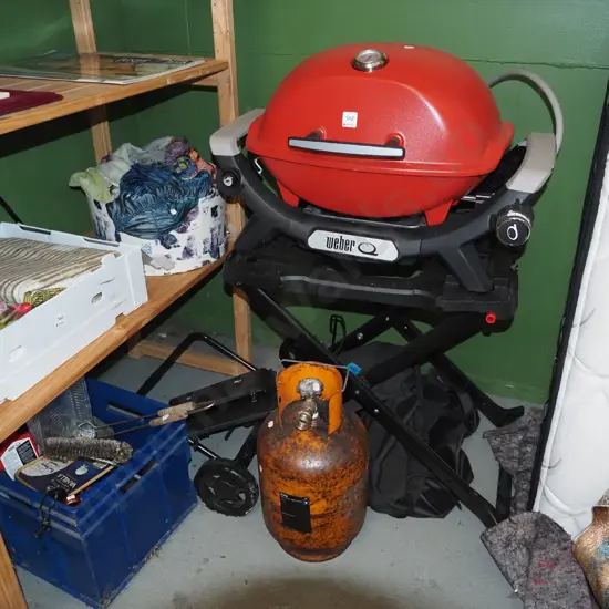 Weber bbq on foldaway trolley, gas bottle, blue tub of accessories - needs a clean