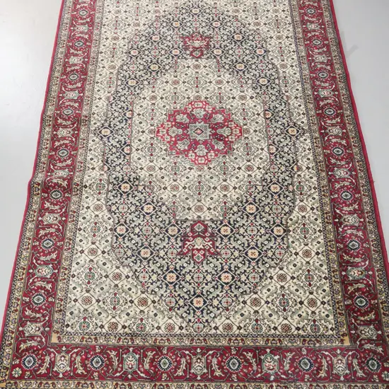 Persian style wool floor rug in dark red, blues, greens and cream - some staining to fringe L-2040 W-1280