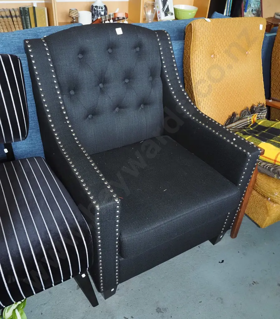 contemporary black upholstered deep buttoned armchair with chrome dome edging Image 1++