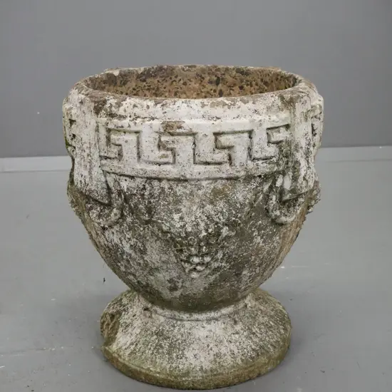 cast concrete garden planter with Greek key pattern and grape decoration on circular fluted base.