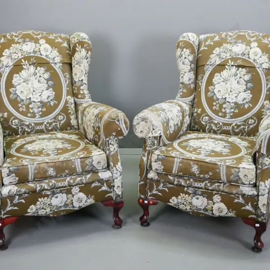pair of mid-century floral upholstered rolled arm wingback chairs on short cab legs. Wear to top of one wing, some