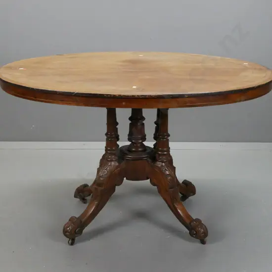 Victorian walnut oval tilt-top loo table on 4-point cathedral base in elm. Some lifting to veneer and fading to surface.