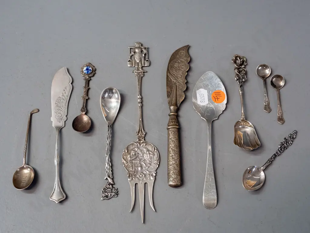 11 decorative and figural cutlery items, most hallmarked or marked sterling silver, one with porcelain ornament. Image 1++
