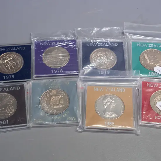 8 New Zealand commemorative dollar coins in plastic cases - 1975, 78,79, 80 81, 83, 85, 86