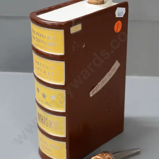 ceramic whisky flask in the shape of a book, with cork stopper and cork-fitted pourer. Some wear to label, tape