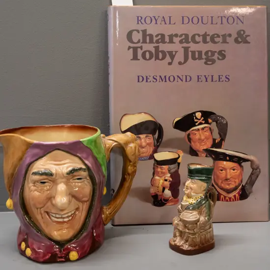 2 Royal Doulton character jugs and a book by Desmond Eyles - larger Touchstone H- 155 and smaller Mr. Micawber H-110