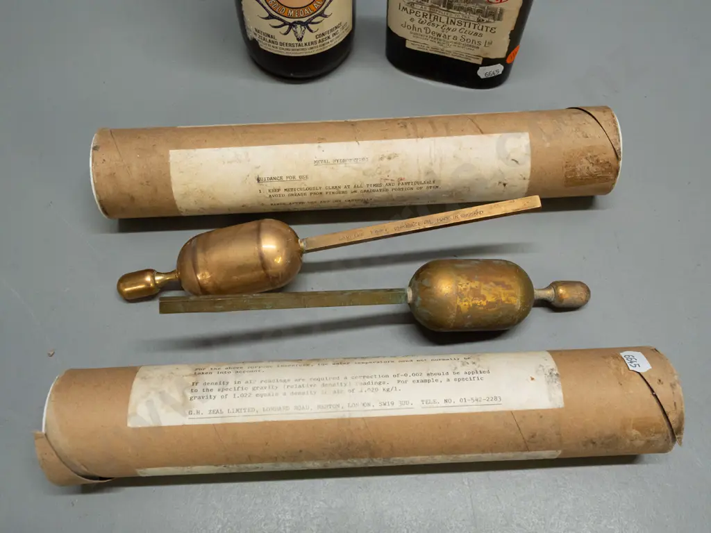 2 brass hydrometers, 1977 Deerstalkers Association Speights beer bottle and John Dewar & Sons whisky, both sealed Image 1++