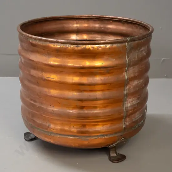 ribbed copper wood bin on 3 copper-plated feet, some dents and wear to painted interior, patched repair in bottom H-340