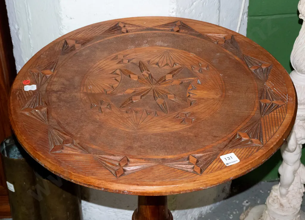 kauri and rimu wine table with geometric-carved circular top on turned column on 3 sweeping legs. Some staining, one leg Image 1++