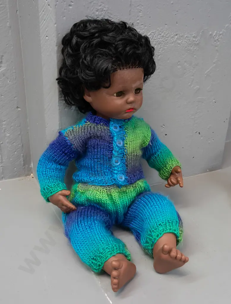 retro plastic doll with open and shut eyes, knitted outfit, back of head has logo with turtle in diamond shape, no Image 1++