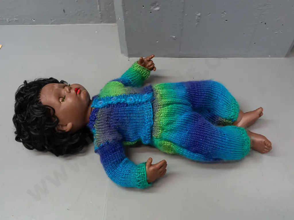 retro plastic doll with open and shut eyes, knitted outfit, back of head has logo with turtle in diamond shape, no Image 1++