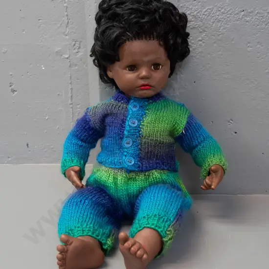 retro plastic doll with open and shut eyes, knitted outfit, back of head has logo with turtle in diamond shape, no