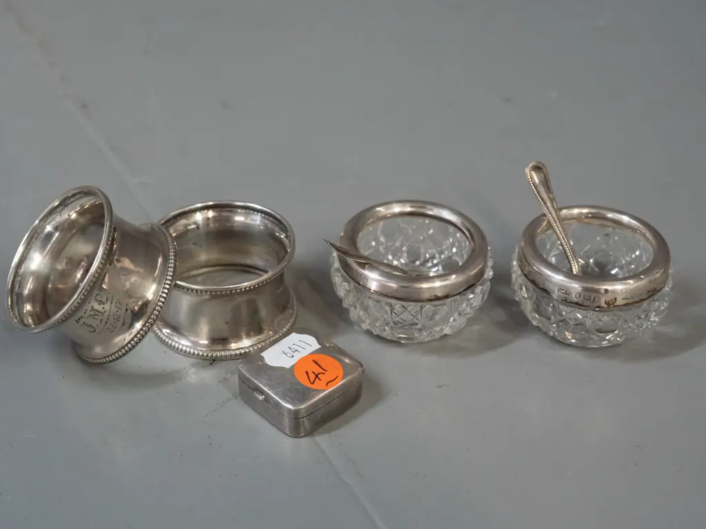 group of assorted sterling silver items - 2 napkin rings with 1917 inscriptions, small pill box and 2 cut glass salts Image 1++
