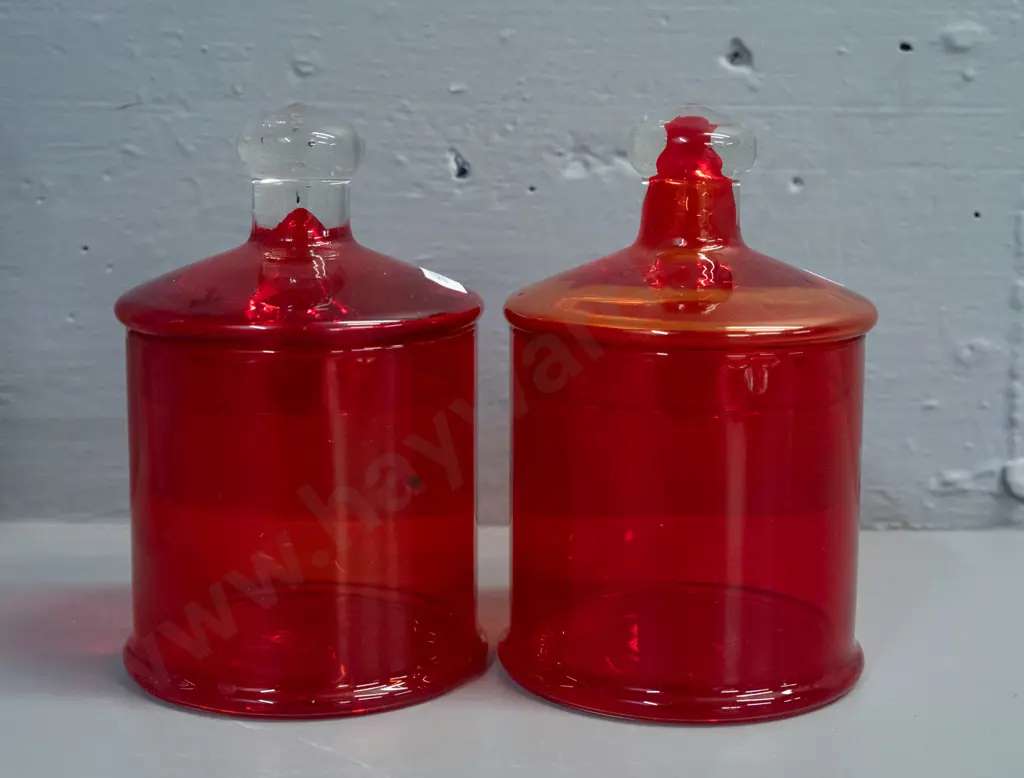 3 glass items - 2 red lidded canisters, one with clear knob, and a blue mottled art glass tall vase or jug with pouring Image 1++