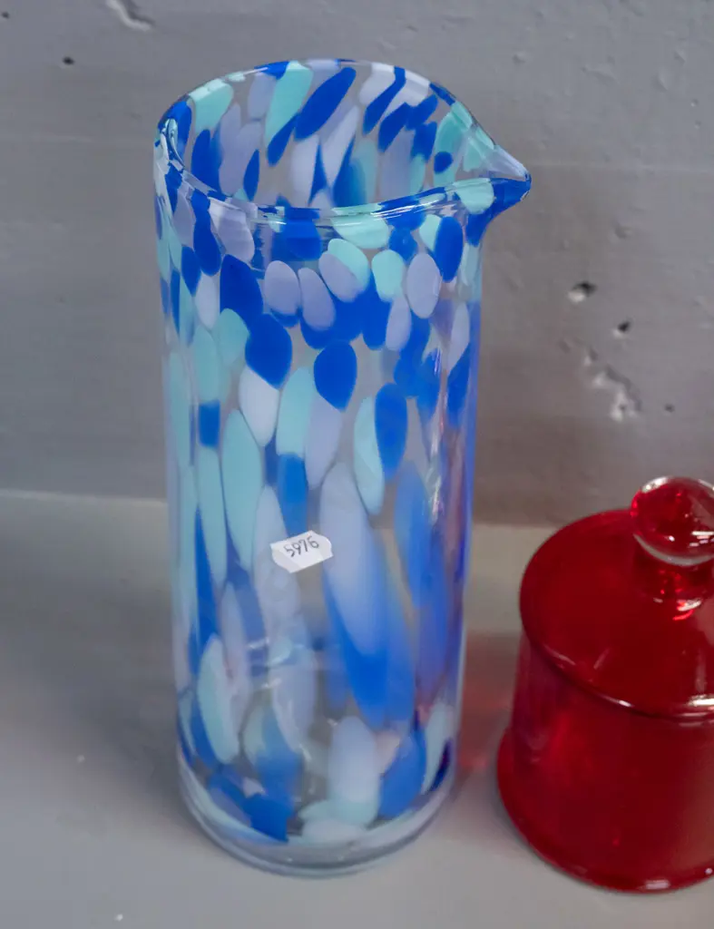 3 glass items - 2 red lidded canisters, one with clear knob, and a blue mottled art glass tall vase or jug with pouring Image 1++