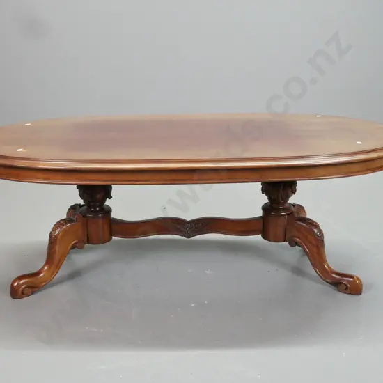reproduction mahogany coffee table with carved double pedestal base and shaped stretcher rail - top surface has some