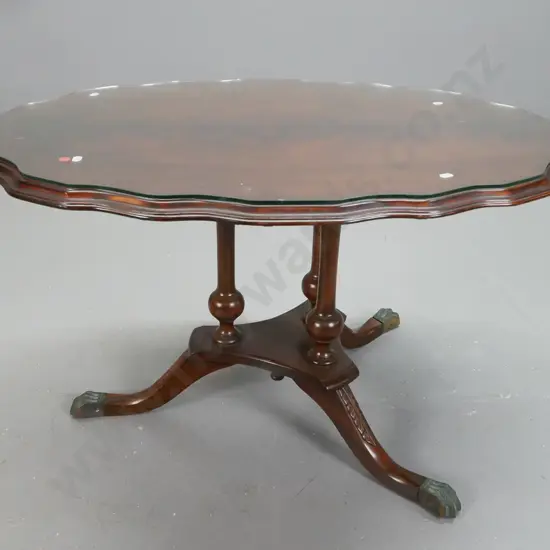 reproduction mahogany veneered serpentine shaped side table on 3 point base w/carved legs on brass lions paw