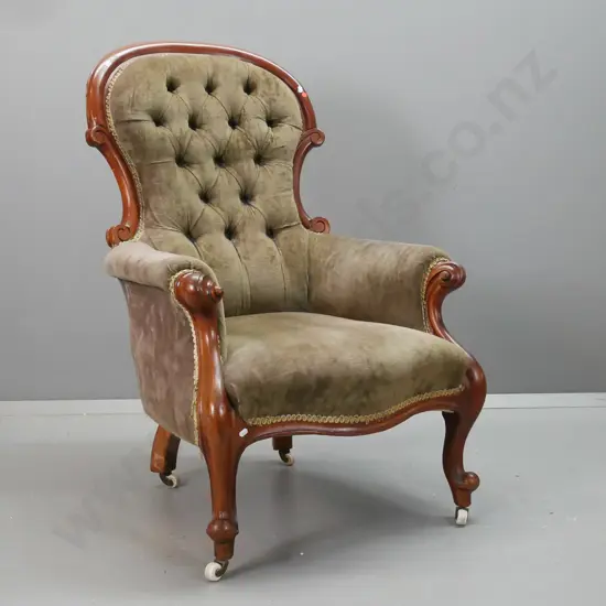 Victorian cedar armchair in olive green velvet w/ deep button back, carved arm supports, cab leg, porcelain casters -