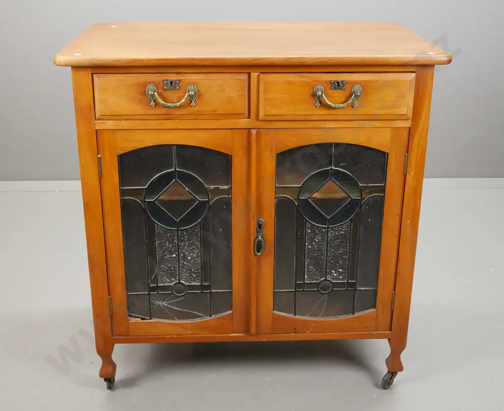Edwardian rimu cupboard with 2 drawer, 2 leadlight cupboard doors, with panelled sides, on casters. One cracked piece of Image 1++