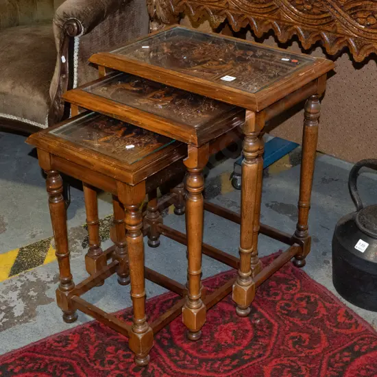 asian set of 3 nesting tables with carved scenic tops covered with inset glass panels with turned supports and stretcher