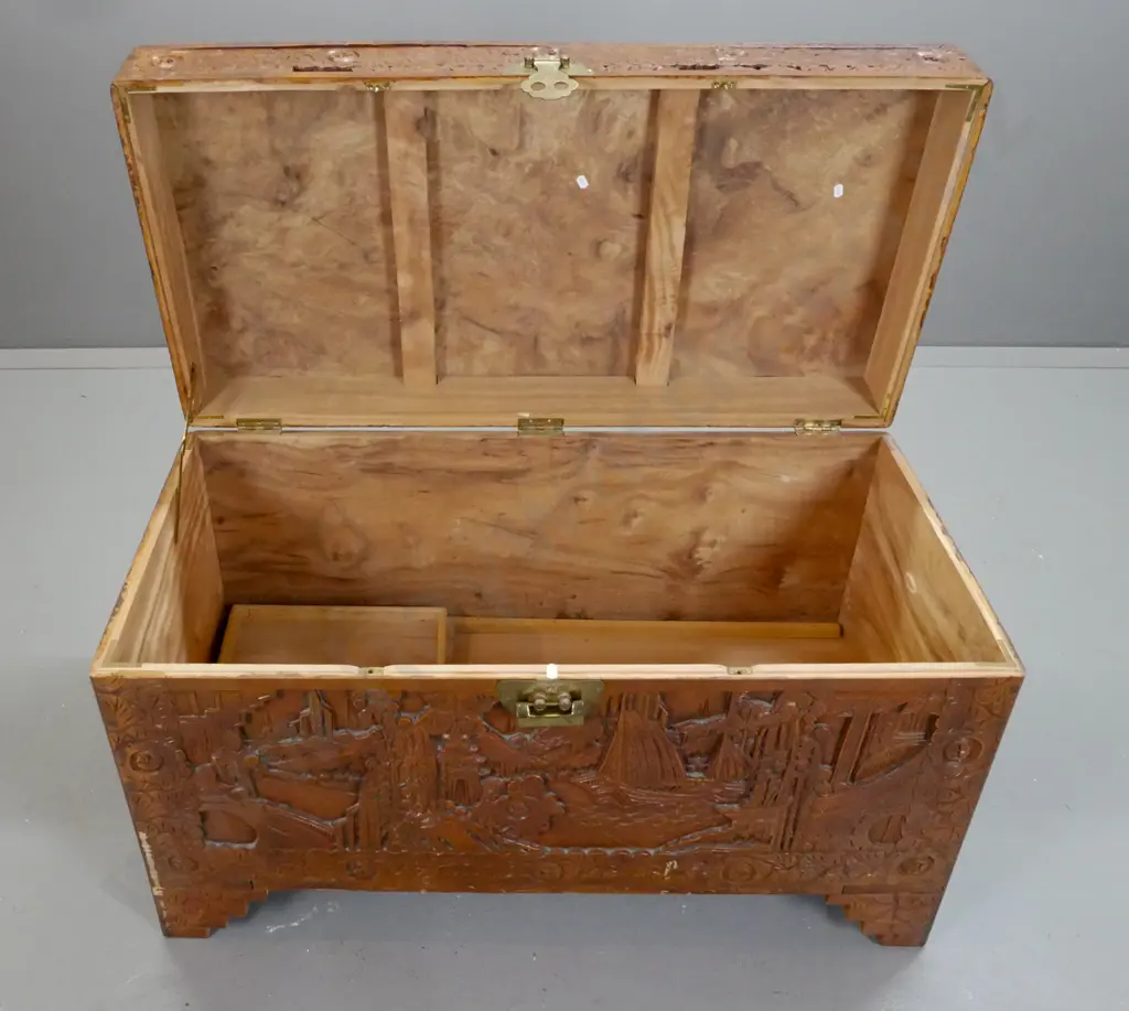 Chinese camphorwood chest with profusely carved scenic panels, tray inside, brass split-key lock, scallop shape Image 1++