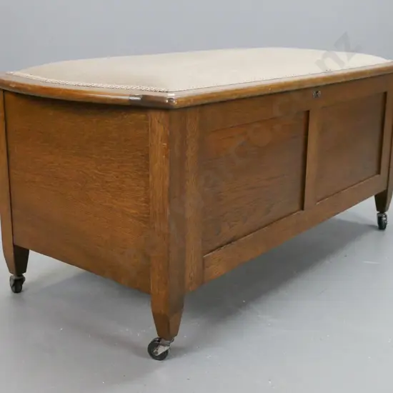 Art deco oak blanket box, with upholstered top, 2 panel front on castors, lock is broken