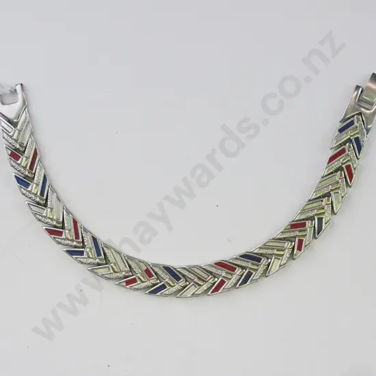 Silver bracelet, links in a chevron pattern. Some links are gold, blue and red.