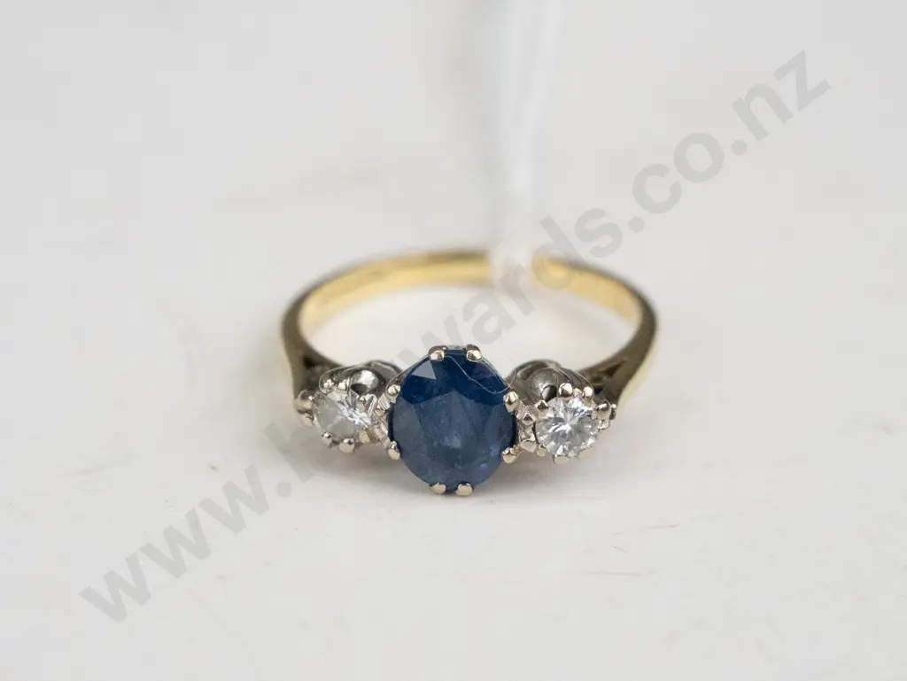 18 ct Gold ring with a sapphire in the middle and diamonds either side. Image 1++